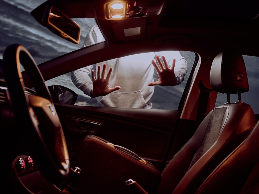 A man's hands against the windows a car with his keys locked inside.