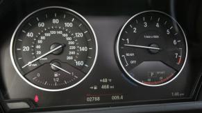 The interior of a 2016 BMW X1 featuring a driver's display with a speedometer (L) and tachometer (R)