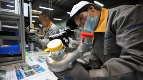 Employees on an assembly line at a Vofon Turbo System factory working on automobile turbochargers