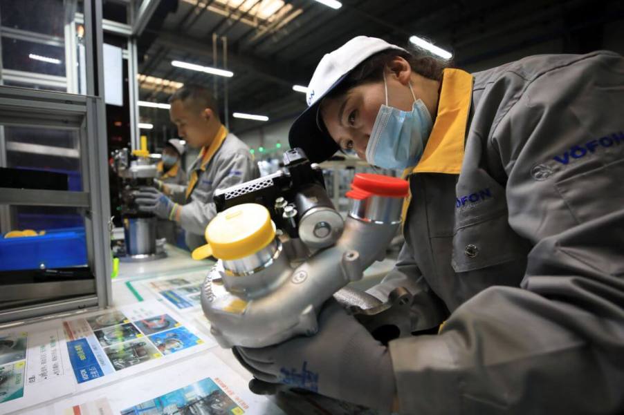 Employees on an assembly line at a Vofon Turbo System factory working on automobile turbochargers