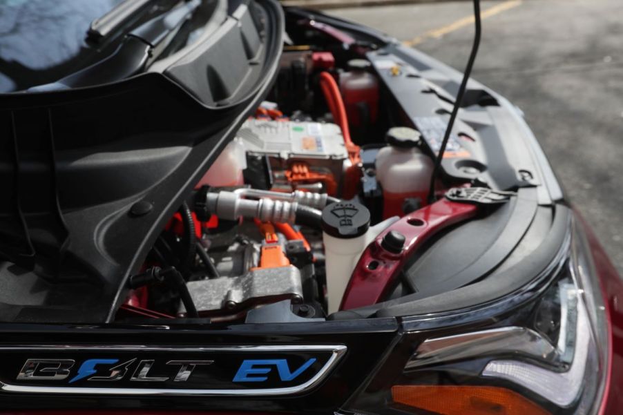 A popped hood of a Chevy Bolt EV hatchback model showing its powertrain and fluid containers