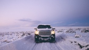 Truck driving in deep winter snow with a plowed road standing snow three feet high on either side