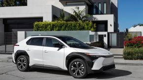 A 2023 Toyota bZ4X XLE compact electric SUV with FWD in Wind Chill Pearl parked outside a luxury home