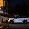 A side profile shot of a plugged in and charging 2024 Jeep Grand Cherokee 4xe plug-in hybrid midsize SUV