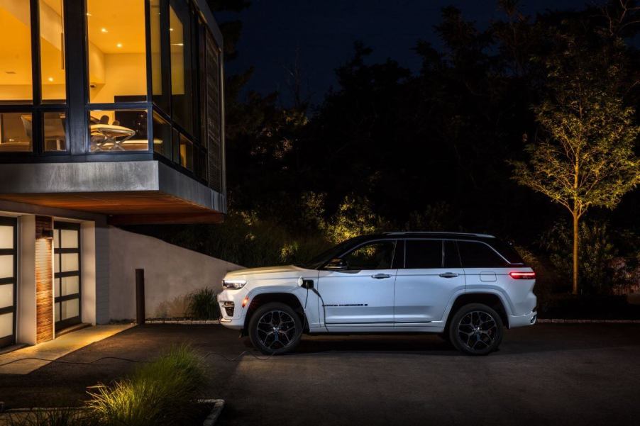 A side profile shot of a plugged in and charging 2024 Jeep Grand Cherokee 4xe plug-in hybrid midsize SUV