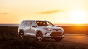 A 2024 Toyota Grand Highlander Limited midsize SUV model parked in the wild as the sun sets behind it