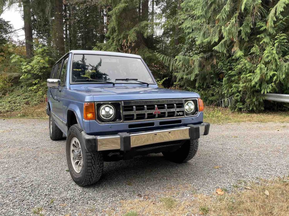 First-gen (1990) Mitsubishi Montero SUV parked off road, the woods visible in the background.