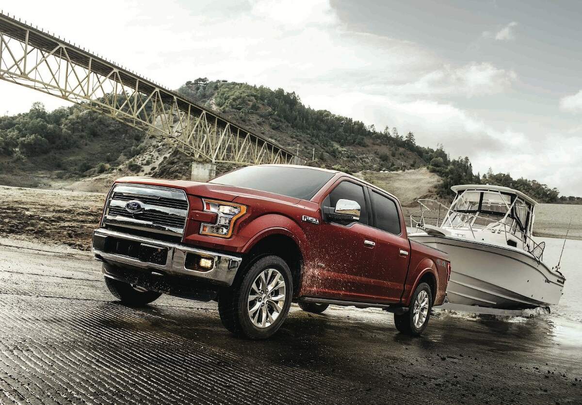 A red 2017 Ford F-150 Lariat tows a fishing boat up a ramp