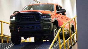 An orange 2021 Ram 1500 doing a demonstration at an auto show.