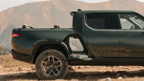 A green Rivian R1T gear tunnel is shown open in right profile view with the desert and mountains in the background