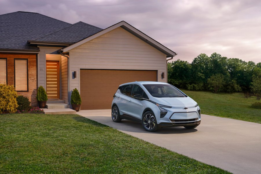 A white Chevy Bolt parked outside of a suburban house. Chevy Bolt complaints are pretty prevalent.