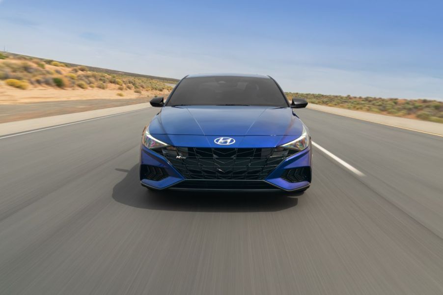 A blue 2023 Hyundai Elantra N driving down an empty road.