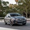 The 2023 Infiniti QX55 in gray driving down a city street.