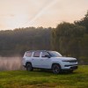 2023 Jeep Grand Wagoneer in white parked in front of a lake and surrounding trees.