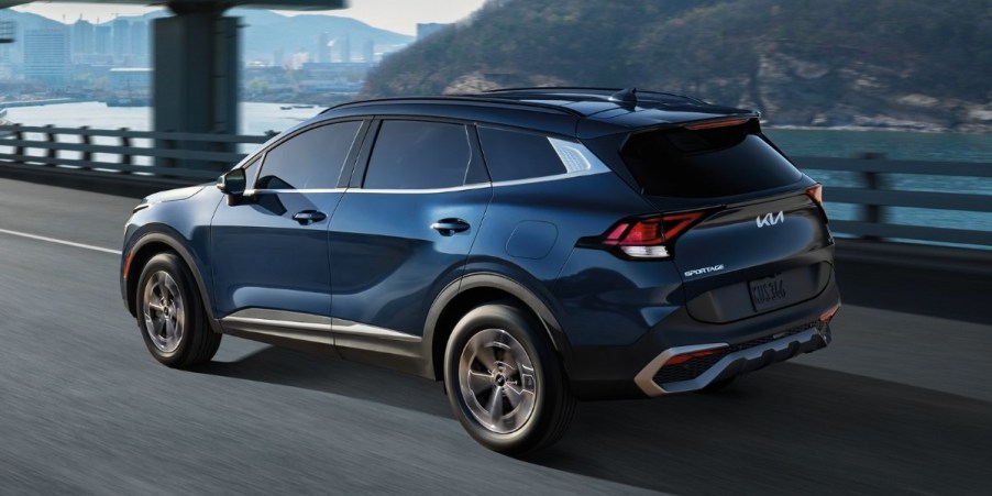 A blue 2023 Kia Sportage Hybrid small hybrid SUV is driving on the road.