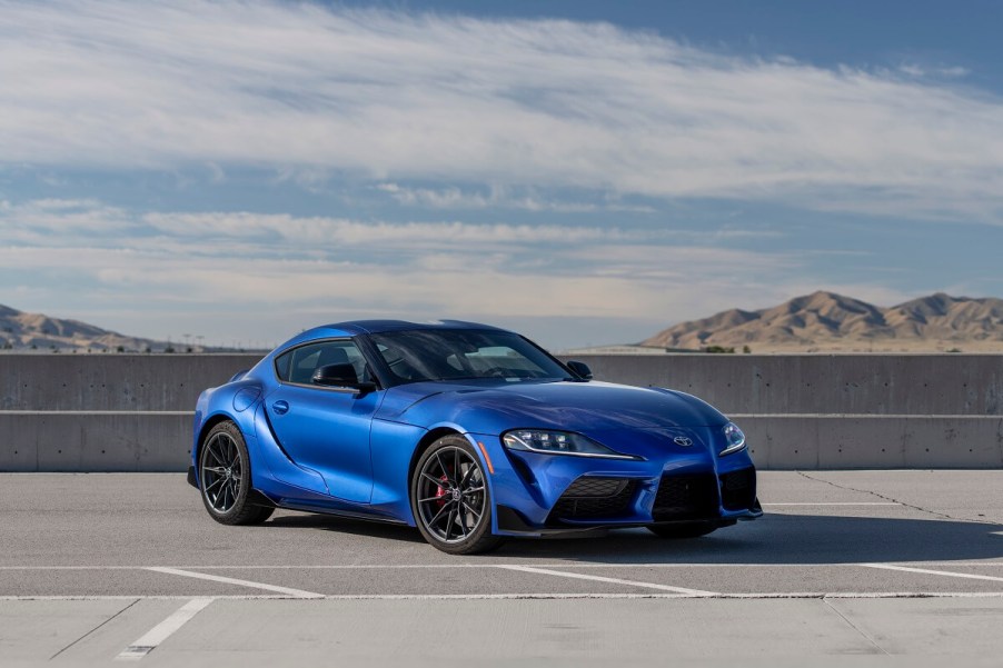 A blue 2023 Toyota GR Supra 3.0 parks on a large asphalt pad.