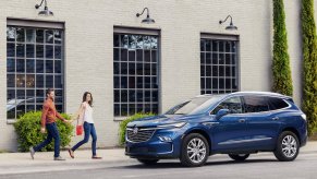 A blue 2024 Buick Enclave parked next to a building. 2024 Buick Enclave features are quite impressive.