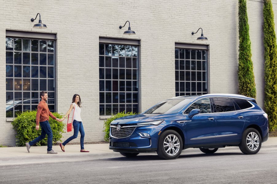 A blue 2024 Buick Enclave parked next to a building. 2024 Buick Enclave features are quite impressive.