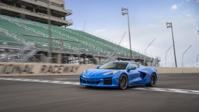 A blue 2024 Corvette E-Ray drives across the line at a track.