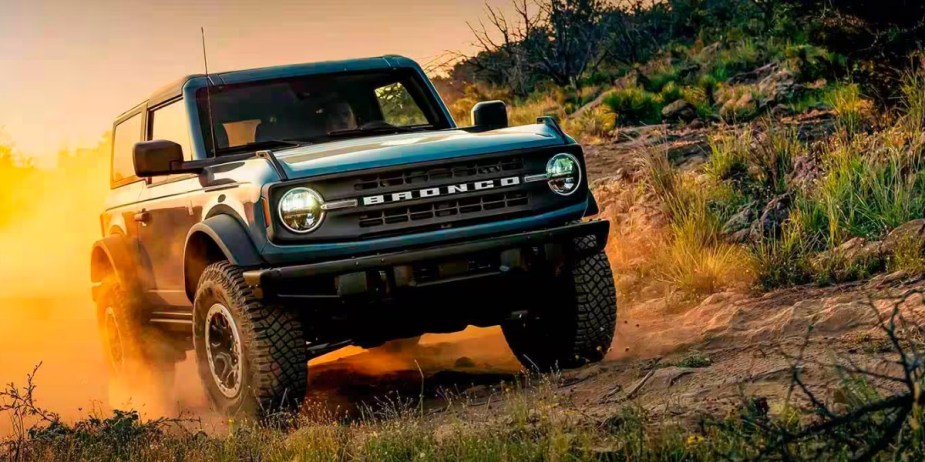 A blue Ford Bronco SUV is driving off-road. 