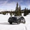 A 2024 Subaru Ascent midsize SUV model traversing in the snow among pine trees and mountains