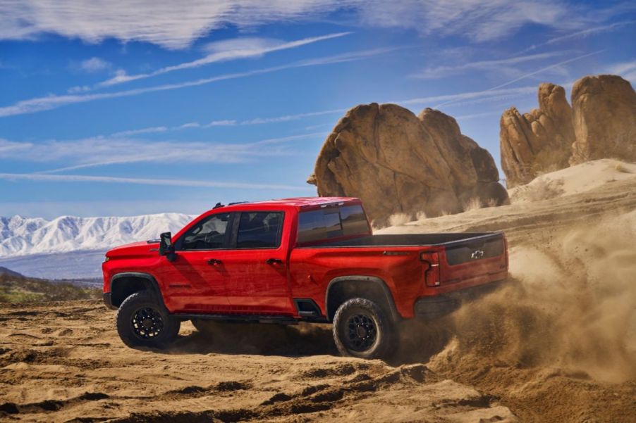 A red heavy duty 2024 Chevrolet Silverado driving off-road.