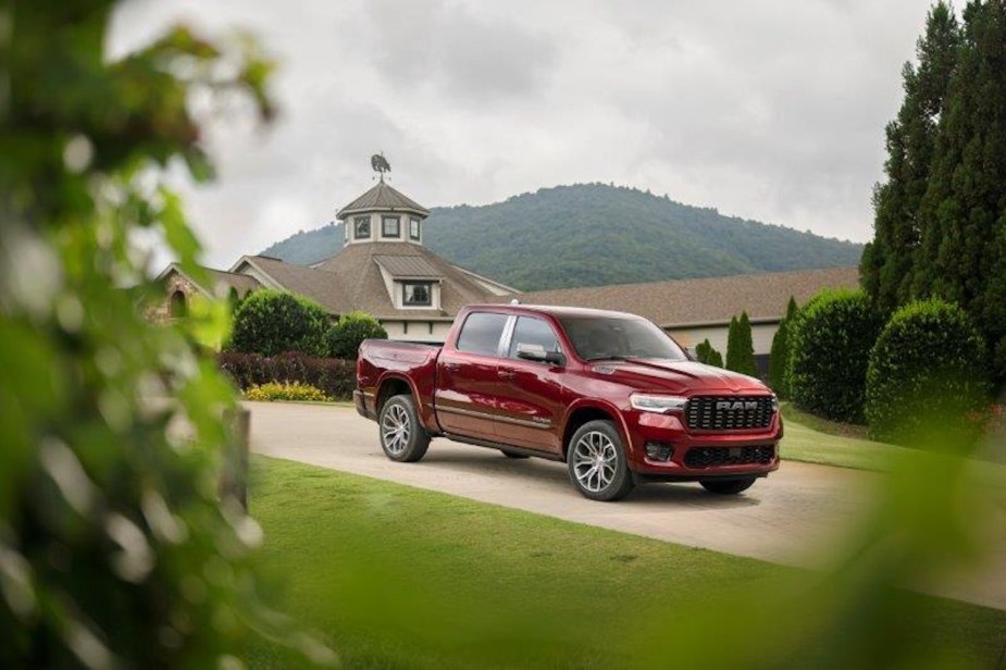 Red Ram 1500 pickup truck parked in front of a barn, trees visible in the foreground.