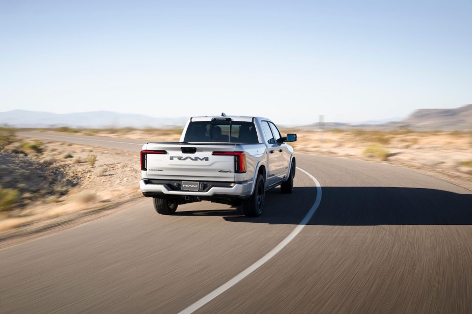 Silver Ram 1500 REV pickup truck driving down a desert road.