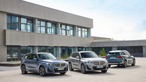 The 2023 BMW X1 among other SUVs in the lineup in front of a modern building. BMW SUV sales are struggling this year.