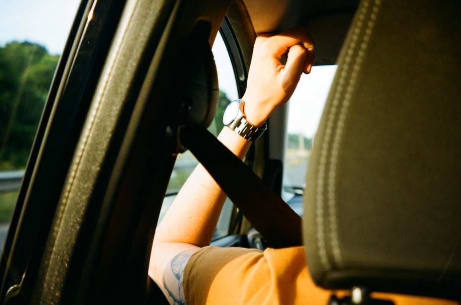 The back of a vehicle driver's seat, with their seatbelt fastened.