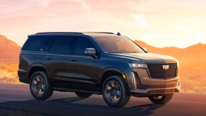 A gray 2024 Cadillac Escalade ESV large luxury SUV is driving.