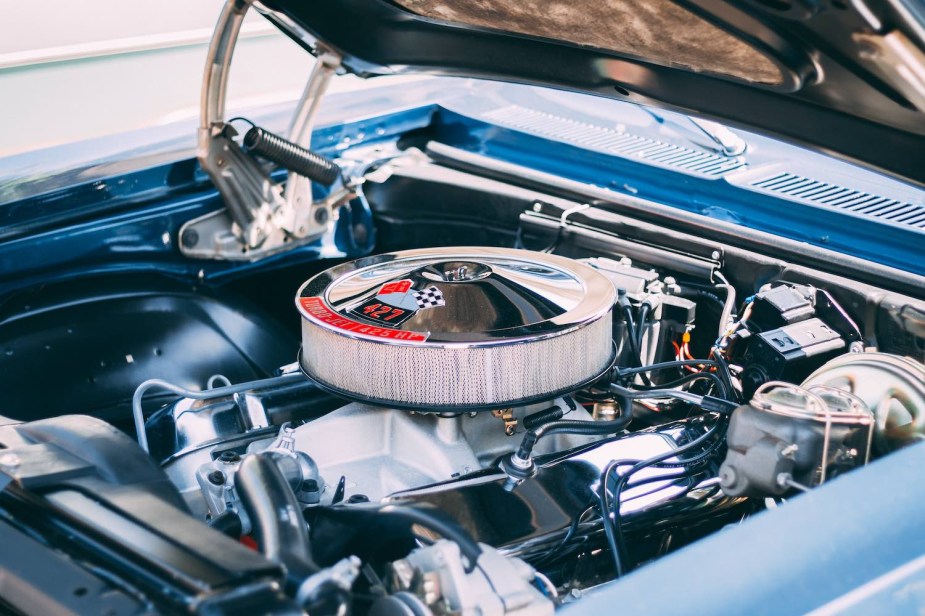 Closeup of the chrome air filter atop a 427 cubic-inch Chevrolet V8 in a blue muscle car with its hood up.