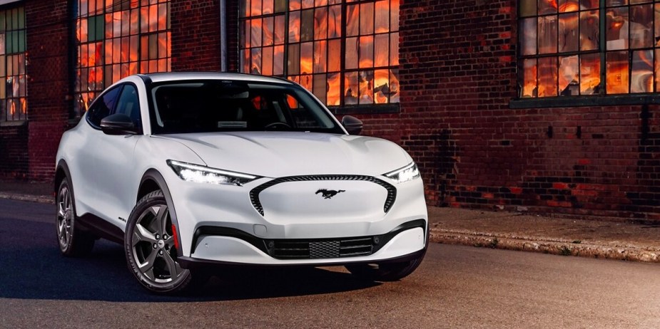 A white Ford Mustang Mach-E small electric SUV is parked outside. 