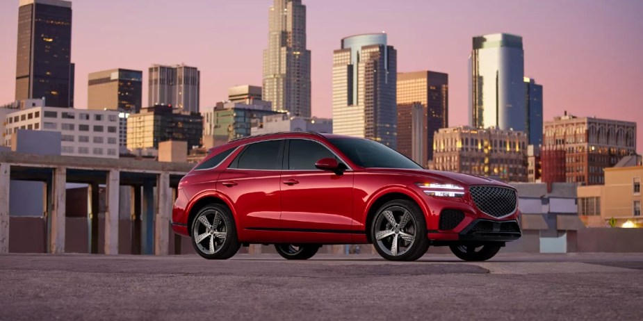 A red Genesis GV70 small luxury SUV is parked. 