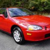 Red 1995 Honda Civic Del Sol front 3/4 sitting in a parking lot in front of some trees