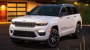 A white 2023 Jeep Grand Cherokee midsize SUV is parked in a driveway.