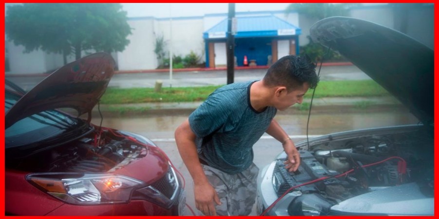 A person is jumpstarting a car.