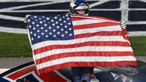 NASCAR driver Justin Allgaier holding the American flag after winning the NASCAR Xfinity Series Alsco Uniforms 300