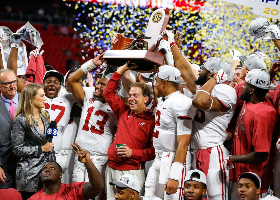 Nick Saban holding the SEC championship trophy with his team, the University of Alabama