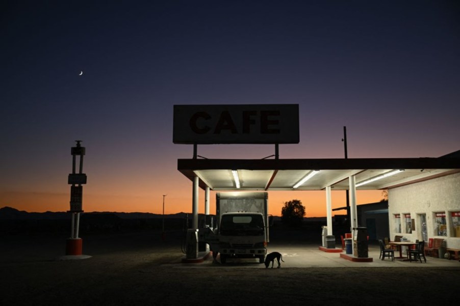 A rural gas station with the lights turned on at dusk.