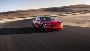 A red Tesla Model S Plaid corners on a desert track.