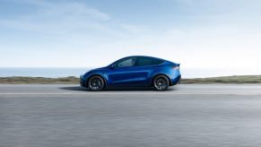 A used Tesla Model Y Long Range in blue cruises an open highway.