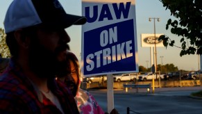 The faces of United Auto Workers Union members holding strike signs outside of Ford's Kentucky plant.