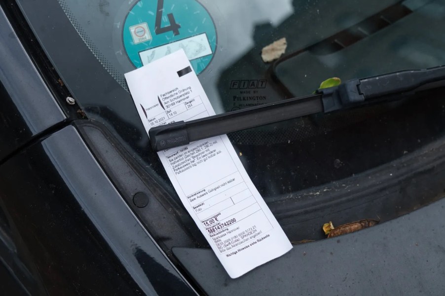 Unpaid parking ticket beneath a windshield wiper.