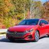 A red Volkswagen Arteon driving down a road in the fall.