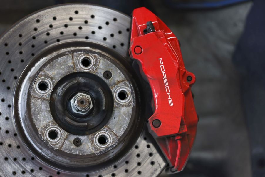 A brake rotor with marks on it and a red Porsche caliper of a Taycan EV sports car model