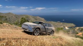 A 2023 Subaru Solterra all-electric compact SUV model covered in dust driving on off-road country trails