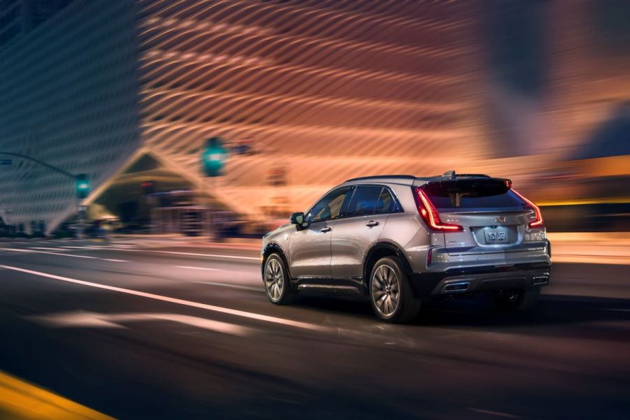 A 2024 Cadillac XT4 subcompact luxury SUV model driving at night through a city near a green streetlight