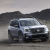 A 2024 Honda Passport TrailSport off-road midsize SUV model kicking up dust as it drives on dirt