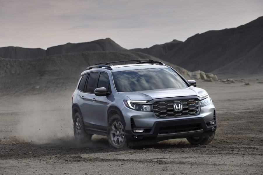 A 2024 Honda Passport TrailSport off-road midsize SUV model kicking up dust as it drives on dirt